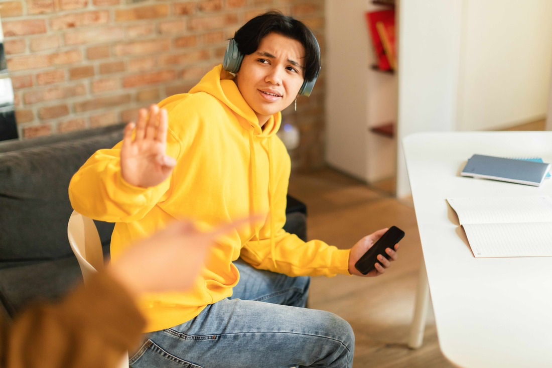 A person wearing headphones and holding a phoneDescription automatically generated
